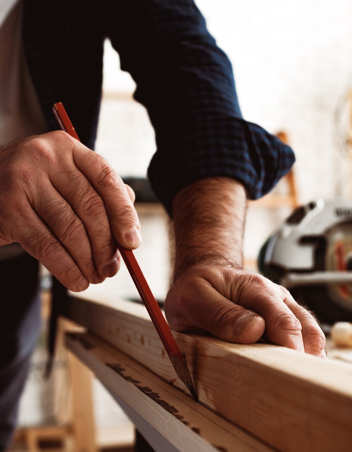 carpenter makes pencil marks on a wood plank