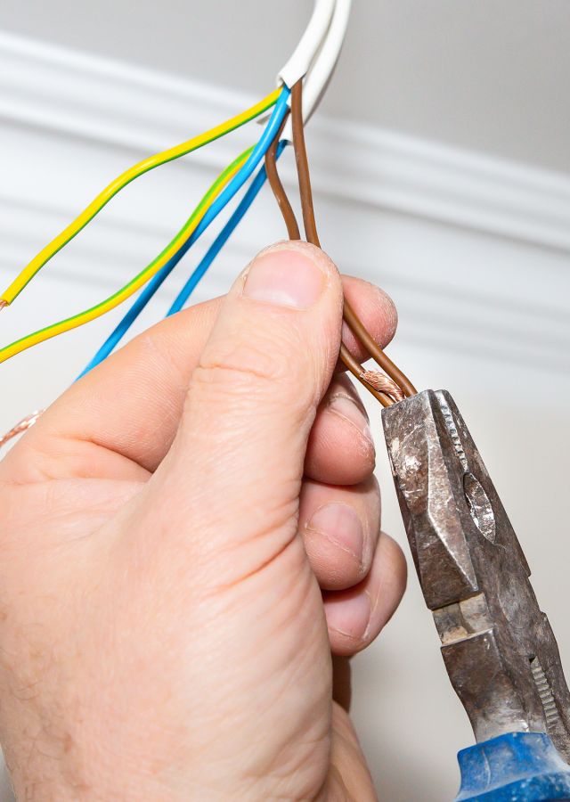 Close image of the hands of a man working on cables with pliers 